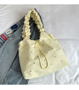 Detail of cream pleated tote bag with rhinestone accents and drawstring closure