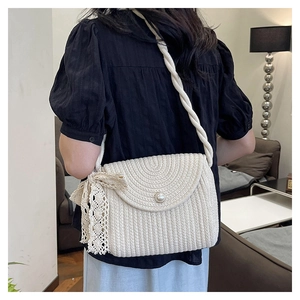Detailed view of white woven crossbody bag with pearl clasp and delicate lace bow accent
