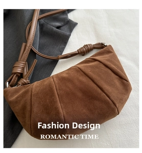 Close-up of brown suede crossbody dumpling bag featuring pleated texture and braided strap