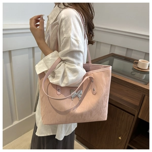 Pale pink tote bag with pleated texture and silver butterfly detail on female model