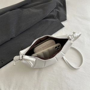 White pleated crossbody crescent bag showing spacious interior with phone and wallet