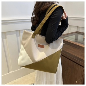 Model wearing a large canvas tote bag with geometric color blocks and leather fashion patch