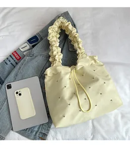 Cream pleated tote bag with silver studs compared to iPad for size visualization