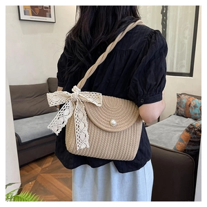 Detail of woven straw shoulder bag featuring a lace bow and large pearl buckle closure