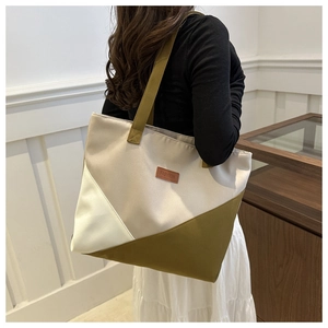 Detail of a large canvas tote bag with color block design worn by a model in a room