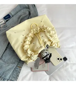 Detail of cream drawstring tote bag showing spacious interior with pleats and rhinestones