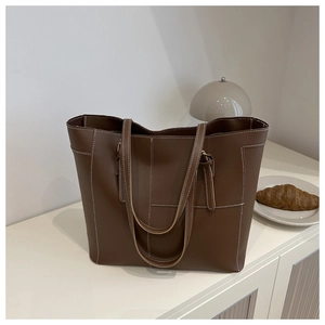Détail du sac cabas marron foncé avec coutures contrastées blanches et texture élégante
