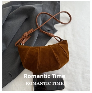 Detailed top view of a brown suede croissant bag showing pleated texture and phone size reference