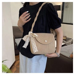 Detail of summer straw crossbody bag with pearl clasp and delicate lace bow accent