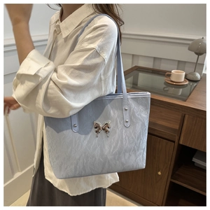 Detail of light blue wrinkled texture tote bag with silver butterfly metal ornament