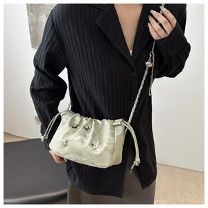 Detail of light green drawstring bucket bag with silver butterfly charms and chain strap