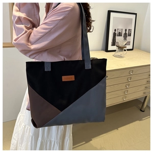 Detail of color-block canvas tote bag with fashion tag held by model in interior