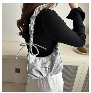 Detail of silver metallic crescent bag with 3D butterfly buckle and ruched shoulder strap