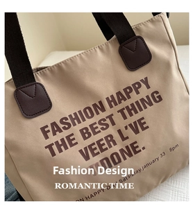 Detail of beige tote bag featuring dark brown ribbon handles and reinforced leather patches