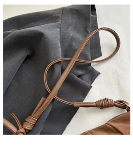 Close-up of brown suede hobo bag with knotted handle and zip detail on blazer