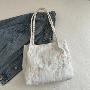 White canvas tote bag with colorful embroidery and ribbon detail for casual daily use