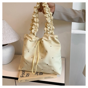 Detail of beige tote bag with silver studs, pleated cloud handle and drawstring closure