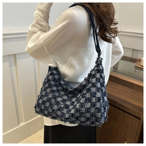 Détail du sac hobo en denim à carreaux avec franges et bandoulière sur un mannequin