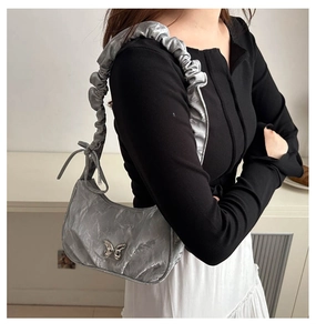 Detail of silver metallic wrinkled shoulder bag with butterfly buckle on model