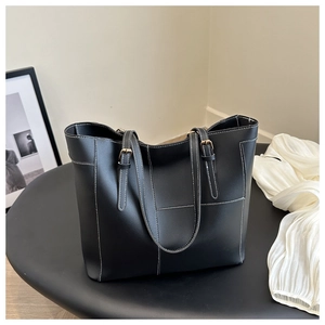 Détail du sac cabas noir avec coutures contrastées blanches et boucle en métal doré