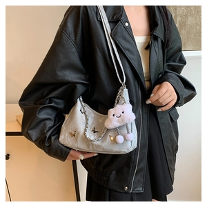Detail view of a silver tote bag with butterfly accents, chain strap and cloud pendant