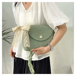 Detail of woven straw bag in green with pearl button and lace bow on a model