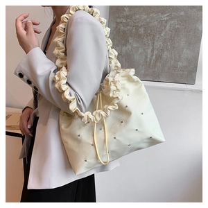 Detailed view of cream ruffled shoulder bag with silver studs on minimalist tote