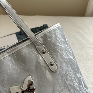 Silver metallic tote bag with wrinkled texture and butterfly metal accent for women