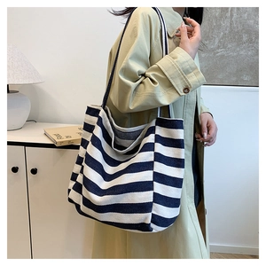 Detail shot of navy and white striped canvas tote bag styled with a beige trench coat