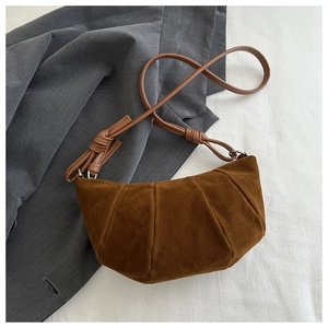 Detailed view of brown suede croissant bag with elegant pleats and knotted leather strap