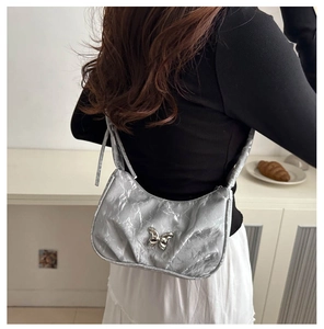 Detail of silver pleated shoulder bag with metallic finish and butterfly buckle detail