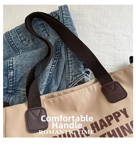 Close-up of reinforced brown handle straps on a beige canvas tote bag for daily use