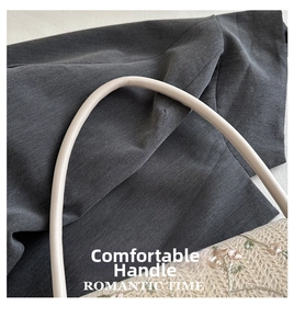Close-up of cream leather cylindrical handle and floral embroidery detail on straw bag