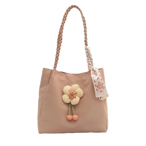 Pink tote bag with woven shoulder strap, 3D floral charm, and patterned silk scarf detail