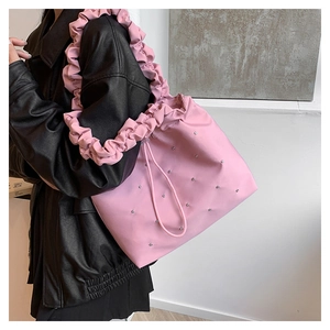 Pink tote bag detail with ruffled shoulder strap and rhinestone accents on model