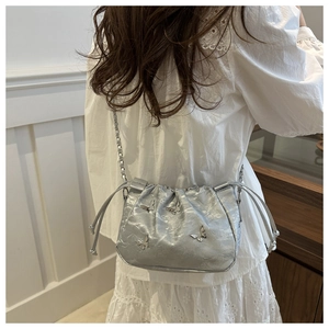 Silver bucket bag detail featuring butterfly charms and stylish metallic chain strap