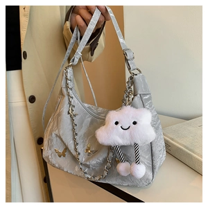 Detail of silver metallic tote bag with chain strap and cute cloud plush charm accessory