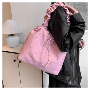 Detail of pink ruffled shoulder strap and silver rivet accents on the chic nylon tote