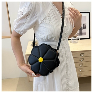 Detail shot of black 3D flower shoulder bag with yellow accent button on a model