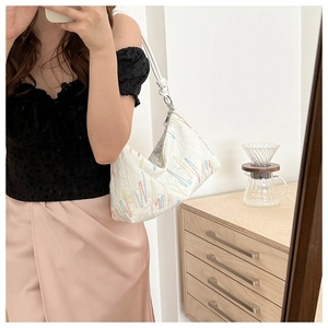 Detail showing white hobo bag with colorful wave embroidery and knotted strap design