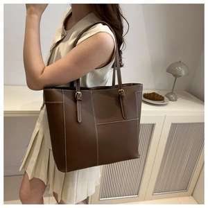 Détail du sac cabas en cuir marron foncé avec surpiqûres contrastées et boucle dorée