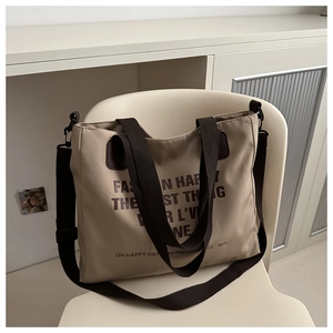 Detail of khaki canvas tote bag with brown handles and adjustable strap on a chair