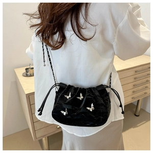 Detail of black velvet bucket bag with silver butterfly accents and chain strap