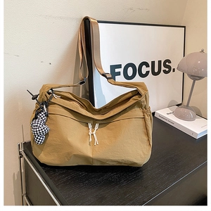 Détail du sac cabas en nylon jaune moutarde avec bandoulière large et charme en damier