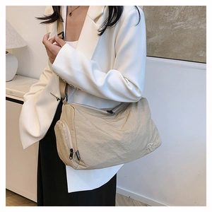 Detail of khaki nylon crossbody bag with adjustable strap and embroidered logo on the side