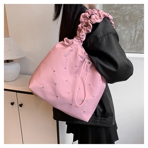 Close-up of pink pleated tote bag with rhinestones and ruffled shoulder strap detail