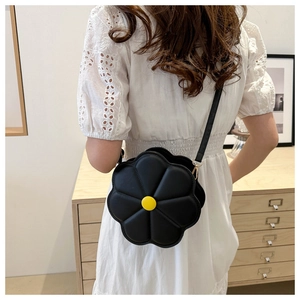 Détail d'un sac à fleurs noir en 3D avec centre jaune porté par un mannequin