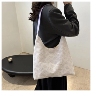 Detail of white textured tote bag with purple straps in a minimalist urban setting