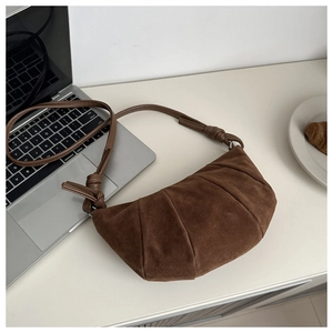 Detailed view of a brown frosted crescent bag with stitched pleat texture and knotted strap