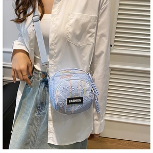 Detail of light blue canvas crossbody bag with FASHION label and colorful stitching